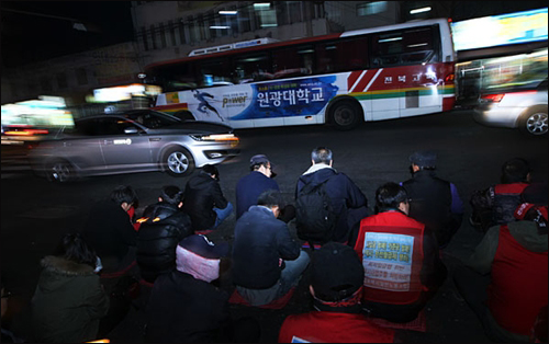 12일 저녁 전주고속분회 조합원들이 촛불집회를 하는 전주시 덕진구 금암동 전주시외버스터미널 앞으로 전북고속 버스가 지나가고 있다.
