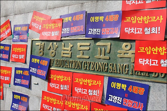  민주노총 경남본부는 2011년 12월 20일 낮 12시 경상남도교육청 후문 앞에서 "고입 연합고사 부활 저지 결의대회"를 열었다. 사진은 경남도교육청 현관 문이 닫혀 있자 조합원들이 간판 옆에 항의 스티커를 붙여 놓은 모습.