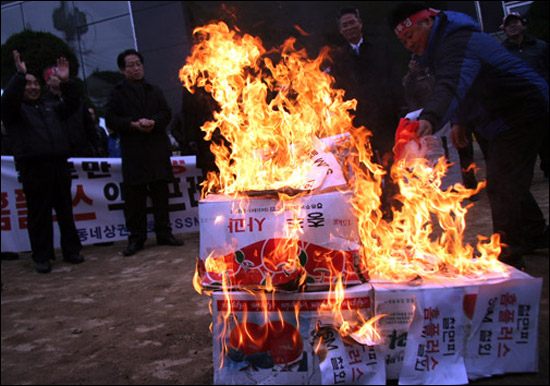 21일, 인천 계양구 홈플러스 익스프레스 효성점 입점 규탄 기자회견에 참석한 상인들이 '철면피 홈플러스 SSM 철회'라고 적힌 상자를 태우고 있다. 