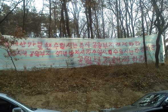 수원시 팔달구 인계동에 위치한 인계3호공원 부지에 내걸린 부직포에 시를 비판하는 글귀가 적혀 있다. 