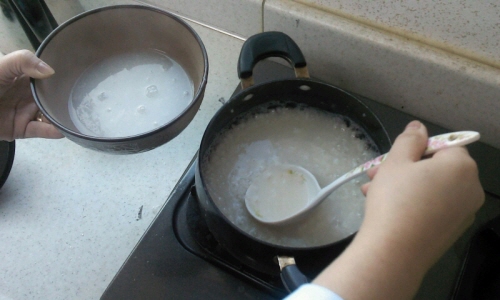 한방 간호사선생님이 쌀죽에서 물을 건져담고 있다.