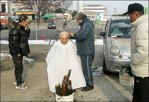  구 군산역 광장 한편에서 노인의 머리를 다듬어 주는 양청무 어른. 
