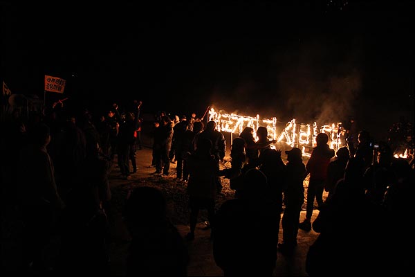 2012년 1월 1일 00:00에 맞춰 '해군기지 결사반대' 구호에 불을 붙인 뒤 서로 보듬어주며 새해 인사를 나누는 사람들.