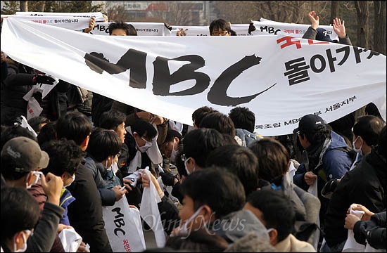 총파업에 돌입한 MBC 노조원들이 6일 오후 여의도 국민은행 앞에서 김재철 사장의 퇴진을 촉구하며 대형 현수막을 펼치고 있다.