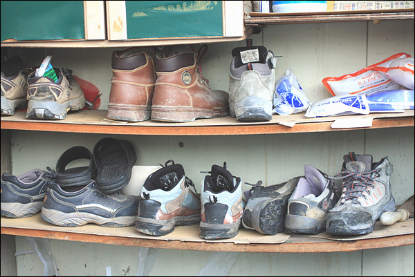 휘어진 신발장에 놓여진 작업화가 서민의 삶을 보여준다.