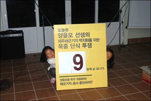 한국영화평론가협회 양윤모 전 회장이 구속수감되어 옥중에서 단식을 이어가는 가운데, 마을 어린이들이 단식 기간을 알리는 패널을 들고 서 있는 모습이다.