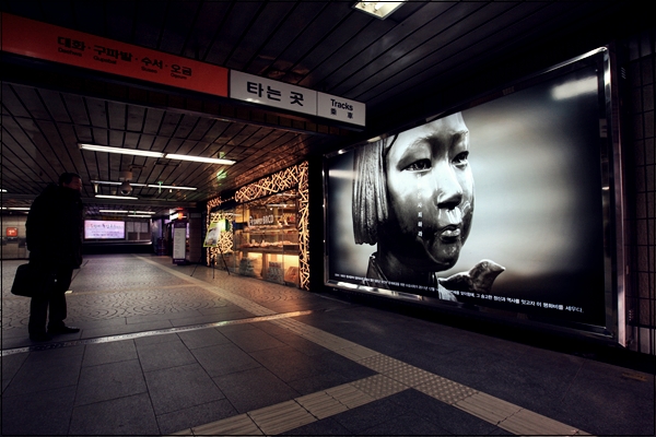 
한시민이 서울 지하철 3호선 안국역 4번출구 안쪽에 '평화비'를 소재로 한 사진광고를 유심히 바라보고 있다.