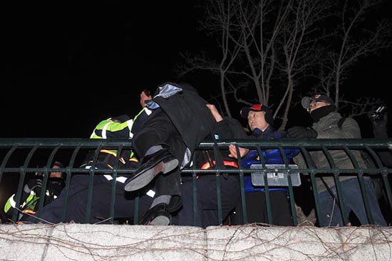 25일 저녁. 경찰은 청계천에서 지상으로 올라오는 모든 계단을 철저히 차단하자 이에 격분한 한 시민이 청계천 난감에 매달리고 있다.