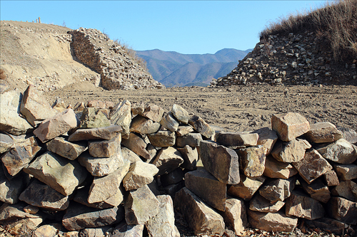 복원을 기다리고 있는 돌들. 무너진 성벽 사이로 소백산맥 자락이 보인다.
