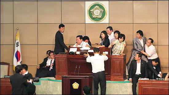 2009년 안산시의회에서 당시 한나라당이 돔구장 문제 날치기 처리를 위해 단상을 점거한 민주당 의원들과 몸싸움을 하고 있는 모습. 연단 가운에 젊은 여성 시의원이 박선희 후보다. 