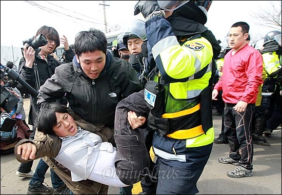  지난 3월 9일 오전 제주도 서귀포시 강정마을 해군기지 공사 현장 앞에서 마을주민이 강제연행을 규탄하며 호송차량의 이동을 막자, 경찰들이 이를 저지하고 있다.