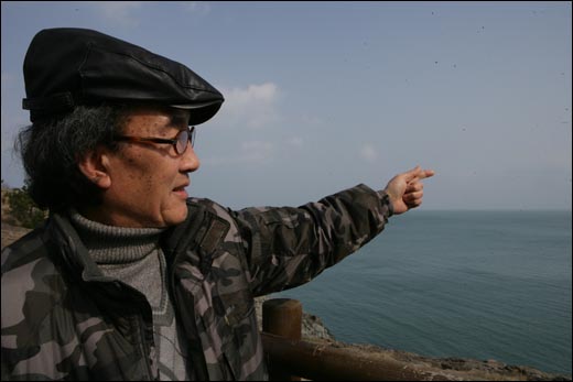 박진용 화백이 그의 작품 무대가 되는 여수 바다를 가리키고 있다.