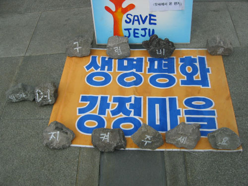 지난 19일 오후, 한국독립영화협회의 '구럼비 발파 중단'을 요구하는 일인시위에 강정마을에서 가져온 펼침막과 돌 위에 '생명형화 강정마을' '구럼비를 지켜주세요. 발파 D-1'이라고 적혀있다.  