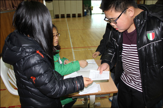 신원확인 후 유권자에게 기표 용지를 배부하고 있는 투표참관인들. 