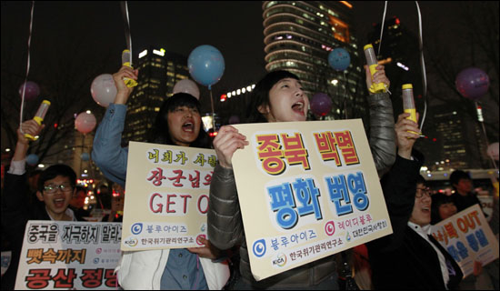 지난 22일 오후 서울 광화문 원표공원에서 열린 천안함 전사자 추모 집회에서 참가자들이 손팻말을 들고 구호를 외치고 있다.  
