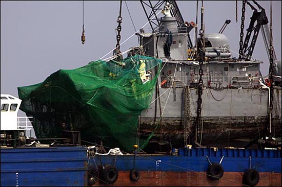 지난 2010년 4월 15일 오후 백령도 인근에서 인양된 해군 초계함 '천안함' 함미가 바지선에 올려져 있는 가운데, 절단면에는 그물이 설치되어 있다.