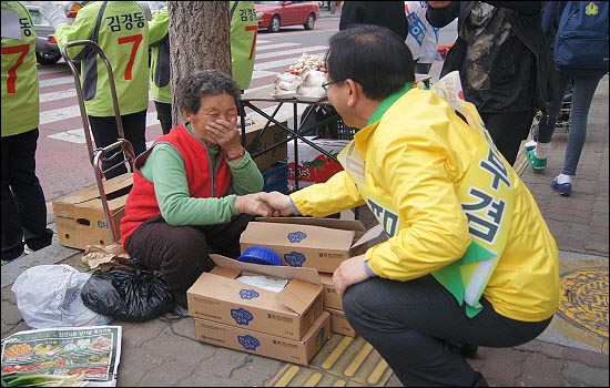 대구 수성갑에 출마한 민주통합당 김부겸 후보가 시장에서 할머니의 손을 잡으며 지지를 호소하고 있다.