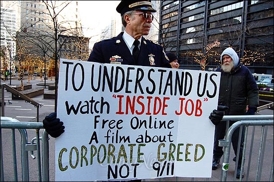 2011년 12월 23일 월스트리트 쥬커티 파크 봉쇄 때 그 앞에 나와 시위하는 예비역 군인. 그가 든 펫말에는 '미국을 이해하기 위해 무료 영화인 "Inside Job 내부자 거래"를 보자. 기업의 탐욕"이라고 적혀 있다. 