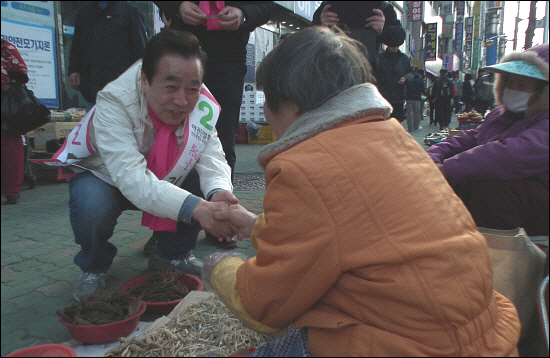 민주통합당 김정길 후보가 개금골목시장에서 유권자와 악수를 나누고 있다. 
