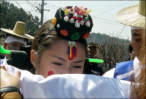  원삼족두리 차림의 신부가 수모의 도움을 받으며 가마에서 내리고 있다.
