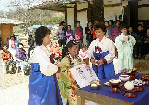  교배례를 올리는 신부. 수모로부터 술잔을 건네받고 있다. 
