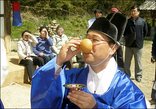  흐뭇한 표정으로 표주박 잔의 술을 마시는 신랑. 
