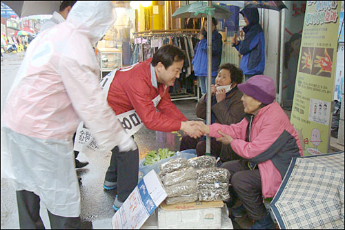 새누리당 김용남 후보가 정자시장에서 빗속에 선거운동을 하며 노점상 할머니들에게 지지를 당부하며 악수하고 있다. 