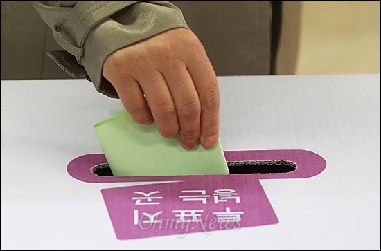 제19대 국회의원 선거날인 4월 11일 오전 서울 마포구 공덕동 주민센터에 마련된 제4투표소에서 유권자가 기표용지를 투표함에 넣고 있다.