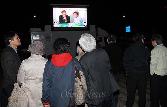 제19대 국회의원 선거가 치러진 11일 오후 서울 서울광장에서 <오마이뉴스> 총선버스 411 특별취재팀이 대형 모니터 차량으로 실시간 생중계 방송을 진행하자, 지나가는 시민들이 모여 개표방송을 지켜보고 있다.