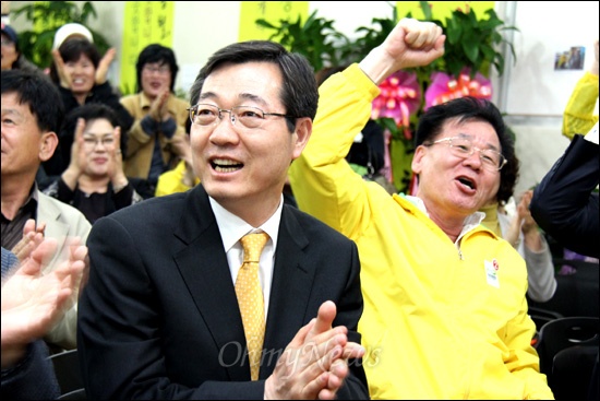 19대 국회의원 총선거에서 '김해갑'에 출마한 민주통합당 민홍철 후보가 11일 저녁 선거사무소에서 개표 상황을 전해 듣고 지지자들의 환호 속에 박수를 치며 기뻐하고 있다.