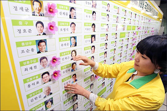 제19대 국회의원선거 개표가 진행중인 11일 밤 민주통합당 당사에 마련된 개표상황실에서 한 당직자가 당선이 확정된 후보 이름에 꽃을 달고 있다.
