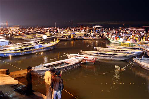 배를 타고 강에서 아르디 뿌자 행사를 구경하는 관광객들 