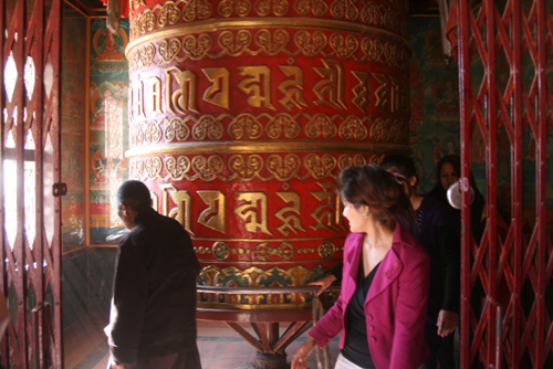 관광객들이 커다란 종을 돌리며 티베트인들의 의식을 따라하고 있다