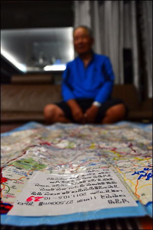 11바퀴를 끝내고 기자의 집에서 휴식을 취하고 있는 남상범 선생이 자신이 걸어온 길을 표시한 지도를 펼쳐 보이고 있다