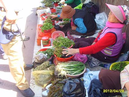  할머니들이 채소를 길에서 팔기 위해서 관광객과 흥정을 하고 있다. 