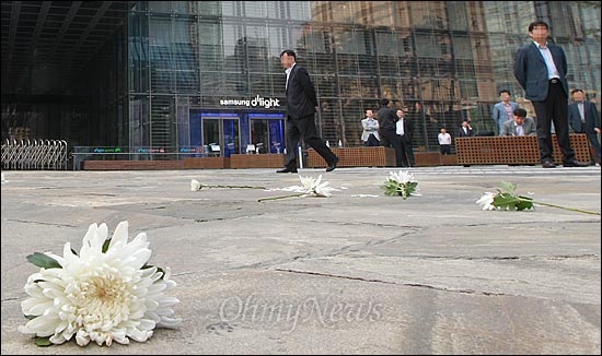 지난해 5월 고 이윤정씨가 삼성반도체 온양공장에서 6년간 일하다 악성 뇌종양으로 세상을 떠난 가운데, 10일 오전 서울 서초구 삼성 본관 앞에서 반도체 노동자의 건강과 인권지킴이 '반올림' 회원, 삼성일반노조, 시민들이 고인의 죽음에 대해 삼성측의 한마디의 사과가 없자, 삼성 본관으로 향해 던진 국화 꽃이 놓여 있다.