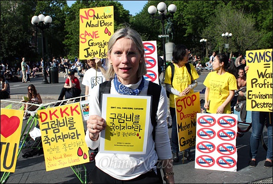 지난 12일 오후(현지시간) 미국 뉴욕 맨해튼 유니온스퀘어에서 제주 강정마을 해군기지 반대를 위한 국제 연대 시위가 열린 가운데, 미국 시민인 미쉘 무어(60)씨가 시위대 앞에서 피켓을 들고 시위대를 응원하고 있다.
