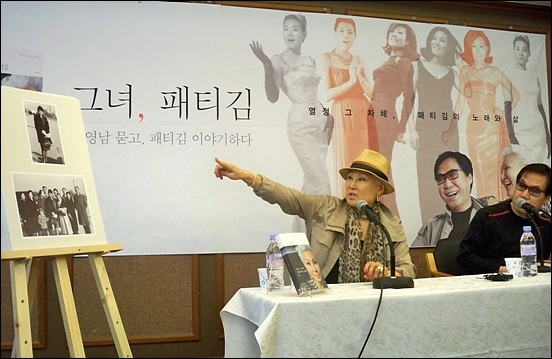 은퇴를 선언 한 가수 패티김이 사인회장에서 지난 날 사진을 보며 설명하고 있다.