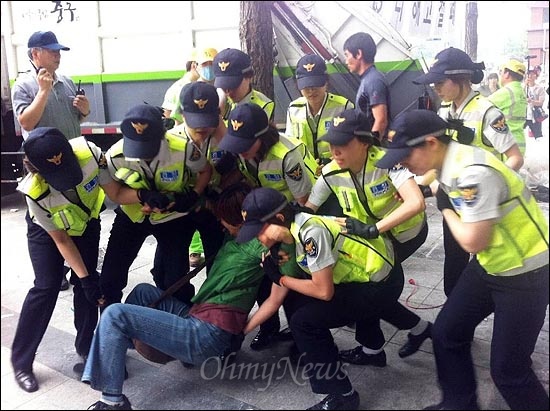 강제철거에 항의하는 여성을 경찰이 끌어내고 있다.