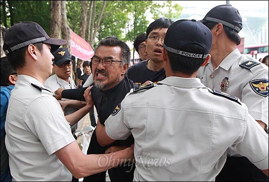  덕수궁 대한문에 마련된 쌍용자동차 정리해고 희생자 22명의 분향소가 강제로 철거된 가운데, 24일 오후 서울 중구 대한문 앞에서 다시 분향소를 준비하기 위해 재설치한 천막을 경찰들이 강제 철거를 시도하자, 김정우 금속노조 쌍용자동차 지부장이 울부짖으며 항의하고 있다.
