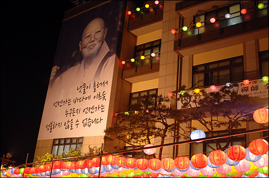 한마음선원외벽에 내걸린 걸게 그림에서 대행 스님은 천연덕스럽게 웃으며 ‘냇물이 흘러서 언젠가는 바다에 이르듯이 누구든지 언젠가는 성불하지 않을 수 없습니다’하며 법문을 하고 있습니다.
