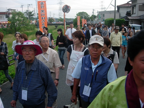 밴드 뒤로 한국참가자들이 행진을 하고 있다. 그 뒤로 마을 주민들이 늘어서서 함께 행진을 하고 있따.