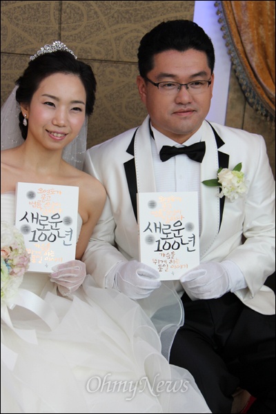 신랑 박진현(39)씨와 신부 김유민(37)씨가 지난 10일 부산의 한 예식장에서 결혼식을 올렸는데, 박씨는 <오연호가 묻고 법률 스님이 답하다, 새로운 100년>이란 책을 구입해 축하객들에게 나눠주었다. 사진은 신랑, 신부가 책을 들어 보이는 모습.
