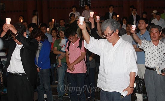  미군 장갑차에 깔려 숨진 심미선양과 신효순양의 10주기 하루 전인 12일 오후 서울 중구 대한문에서 열린 '미선, 효순 10주기 추모 토크 콘서트'에 참가한 시민들이 두 소녀를 추모하기 위해 잠시 묵념하며 촛불을 들어보이고 있다.