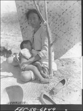 1950. 8. 24. 피난길에 한 어머니가 거적 아래서 아이에게 젖을 먹이고 있다.