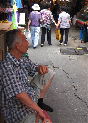 24일 오후 서울 강동구 천호신시장에서 한 가게 주인이 지나가는 손님들을 바라보고 있다.