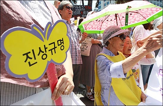  일본 극우단체가 위안부 소녀상에 말뚝테러를 저지를 가운데, 27일 오후 서울 종로구 일본대사관 앞에서 열린 '일본 위안부 문제 해결을 위한 1028차 수요집회'에서 일본군 위안부 피해자 김복동 할머니(87)와 참석자들이 위안부 범죄의 진상규명과 공식 사과를 촉구하며 구호를 외치고 있다.