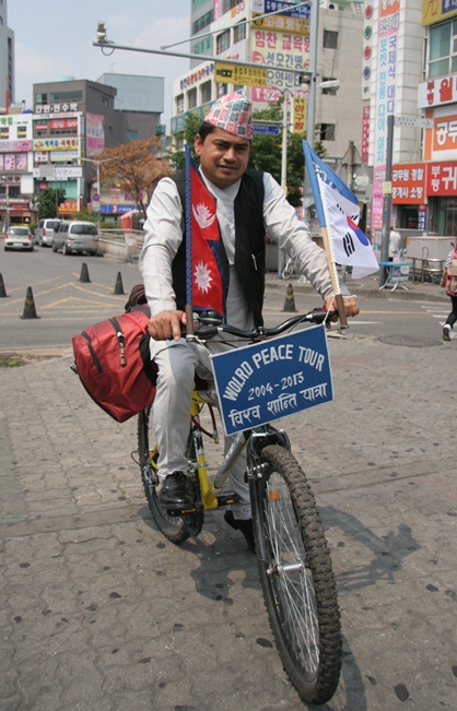 ▲ 자전거를 타고 전 세계를 다니며 평화의 메시지를 전하고 있는 네팔인 록 반두 카르키씨가 부평역 앞에서 포즈를 취했다. 