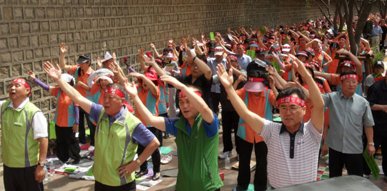 서울메트로 청소용역 노동자들이 집회 마무리 노래를 부르며 양손을 위로해 흔들고 있다.