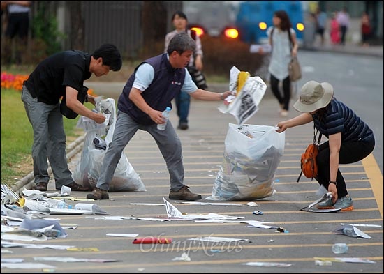 김영훈 민주노총 위원장이 유인물과 손피켓 등 조합원들이 버리고 간 쓰레기들을 봉투에 담고 있다.